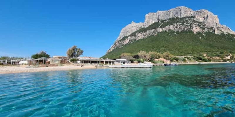 A body of water with a building and a mountain in the background

Description automatically generated